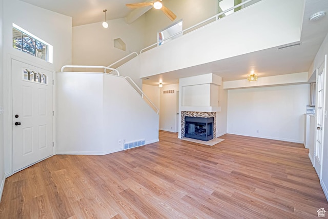 5457 S Break Water Dr W, Taylorsville, UT 84123 - unfurnished living room with a high ceiling, light wood-style flooring, ceiling fan, baseboards, and a tiled fireplace