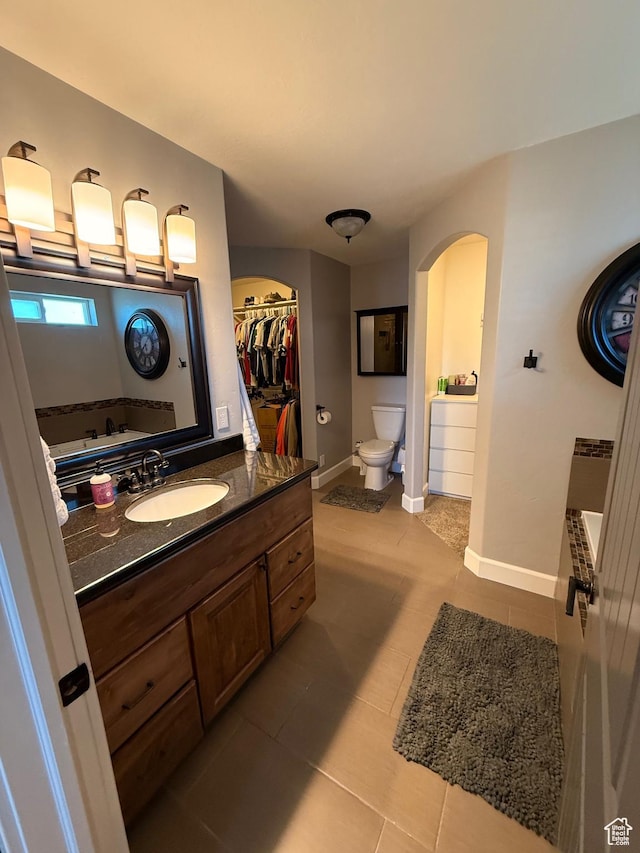 730 S 300 W, Garland, UT 84312 - full bathroom featuring toilet, vanity, tile patterned flooring, baseboards, and a walk in closet