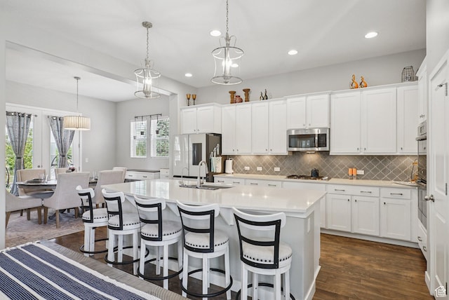 4411 W S Jordan Pkwy, South Jordan, UT 84009 - kitchen featuring a sink, appliances with stainless steel finishes, light countertops, decorative backsplash, and an island with sink
