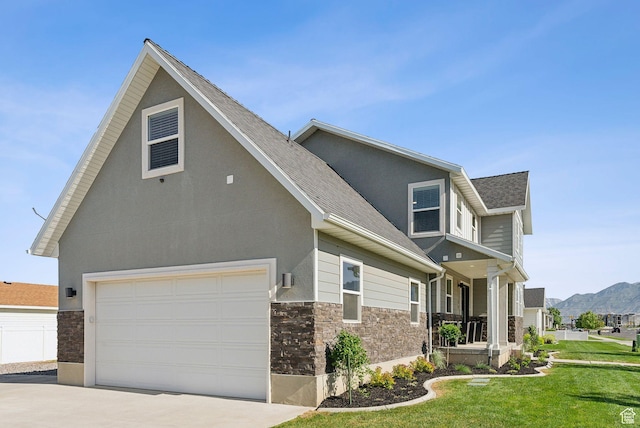 1184 S 2300 E, Spanish Fork, UT 84660 - view of front of house featuring stone siding, a garage, a front lawn, concrete driveway, and covered porch