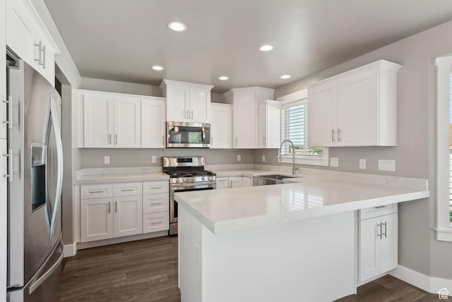 1184 S 2300 E, Spanish Fork, UT 84660 - kitchen with stainless steel appliances, a sink, a peninsula, dark wood-style floors, and white cabinets