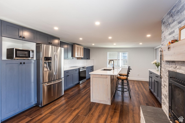 824 N 200 E, Price, UT 84501 - kitchen featuring appliances with stainless steel finishes, a sink, light countertops, a fireplace, and a breakfast bar area