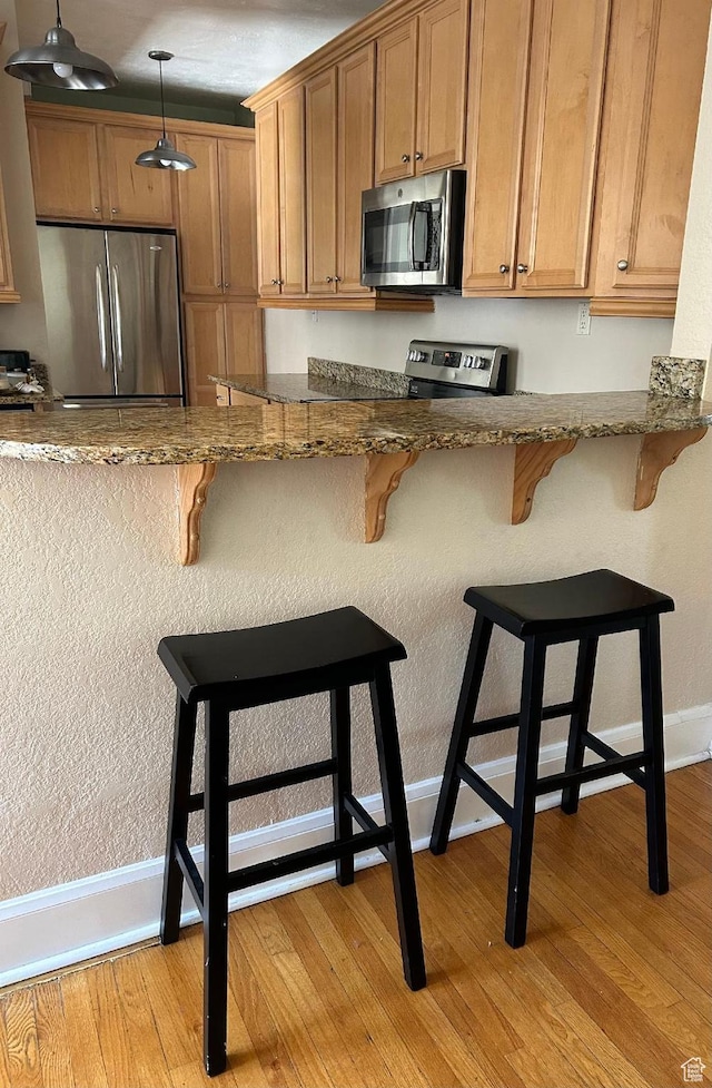 734 S 1300 E, Salt Lake City, UT 84102 - kitchen with stainless steel appliances, baseboards, light wood-style floors, dark stone counters, and hanging light fixtures