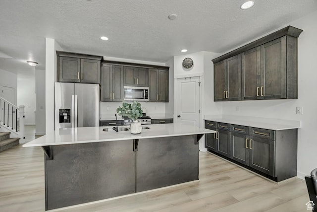 4214 E Sun Crest Dr Unit Lot68, Eagle Mountain, UT 84005 - kitchen with stainless steel appliances, light countertops, an island with sink, dark brown cabinets, and light wood finished floors