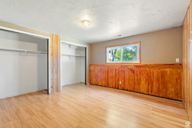 793 E 100 S, Hyrum, UT 84319 - unfurnished bedroom with two closets, light wood finished floors, a wainscoted wall, and wooden walls