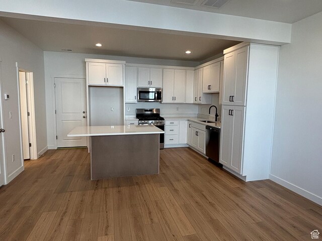 6889 W S Jordan Pkwy, South Jordan, UT 84009 - kitchen featuring appliances with stainless steel finishes, white cabinets, wood finished floors, a center island, and recessed lighting
