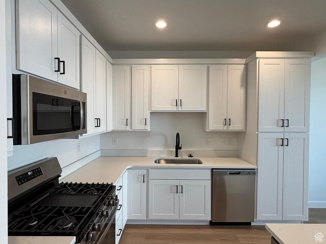 6889 W S Jordan Pkwy, South Jordan, UT 84009 - kitchen featuring appliances with stainless steel finishes, a sink, recessed lighting, wood finished floors, and white cabinets