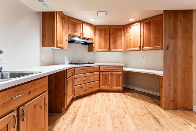 3380 S 930 W, Syracuse, UT 84075 - kitchen with under cabinet range hood, brown cabinets, light wood-style flooring, light countertops, and a sink