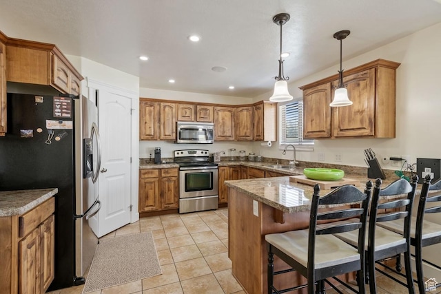 3638 S Blazing Oak Dr, Magna, UT 84044 - kitchen with appliances with stainless steel finishes, a peninsula, a sink, brown cabinets, and decorative light fixtures