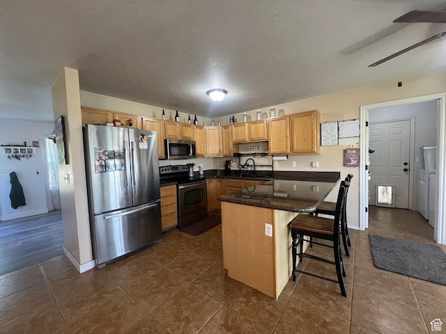 865 E 980 N, Tooele, UT 84074 - kitchen featuring stainless steel appliances, a sink, ceiling fan, dark countertops, and a peninsula