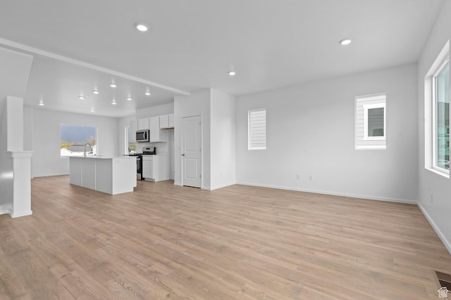 1889 E Thunder Ln Unit 496, Eagle Mountain, UT 84005 - unfurnished living room with healthy amount of natural light, light wood-style floors, recessed lighting, baseboards, and a sink