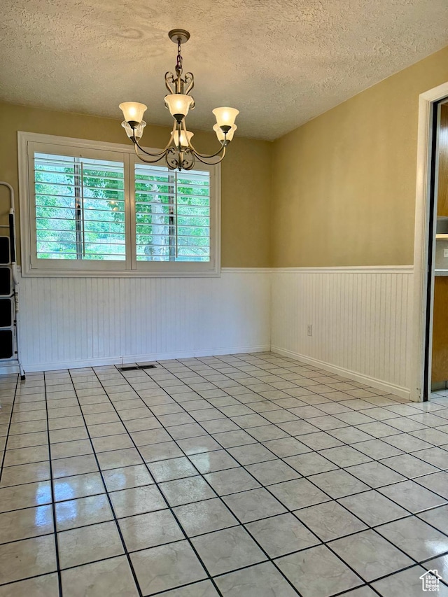 246 N 2800 E, Layton, UT 84040 - empty room with wainscoting, a textured ceiling, a chandelier, and light tile patterned floors