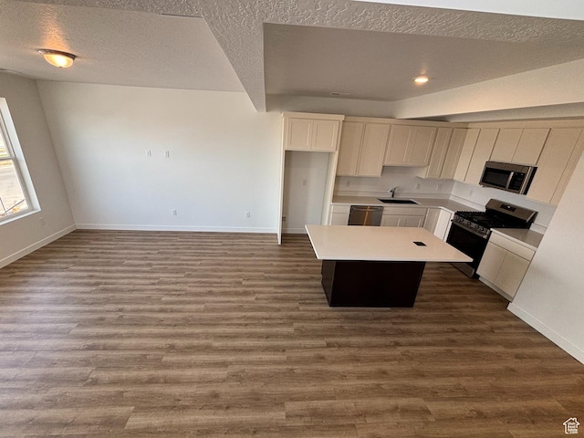 6907 W S Jordan Pkwy, South Jordan, UT 84009 - kitchen with stainless steel appliances, a kitchen island, baseboards, a sink, and a textured ceiling
