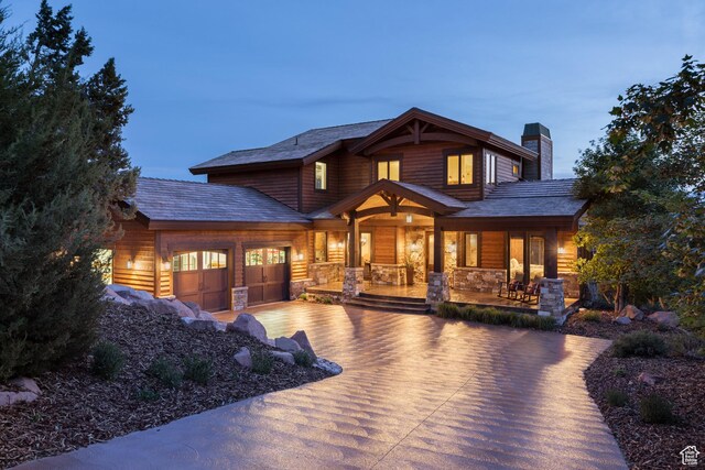 2314 E Flattop Mountain Dr Unit 89, Heber City, UT 84032 - view of front facade featuring covered porch, driveway, a chimney, a garage, and stone siding