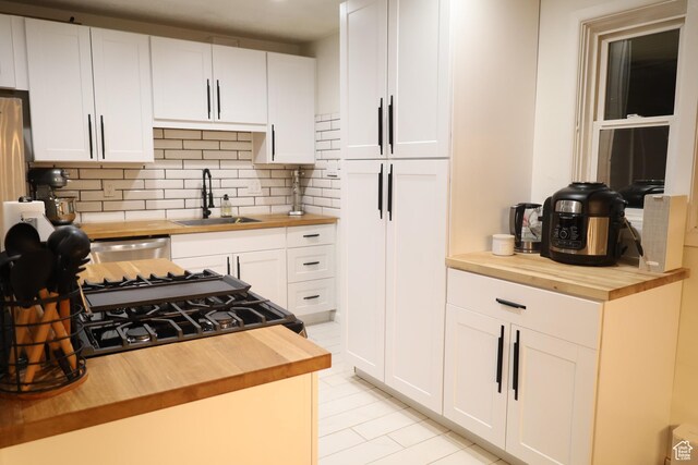 1834 E Cloverdale Rd S, Cottonwood Heights, UT 84121 - kitchen featuring wooden counters, a sink, tasteful backsplash, white cabinetry, and light tile patterned floors