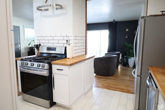 1834 E Cloverdale Rd S, Cottonwood Heights, UT 84121 - kitchen with wood counters, stainless steel appliances, healthy amount of natural light, and white cabinets