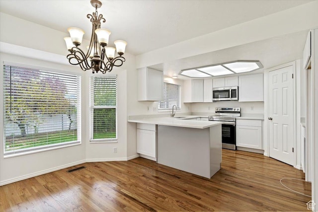 1134 N 2825 W, Layton, UT 84041 - kitchen featuring stainless steel appliances, a peninsula, dark wood-style floors, white cabinets, and a chandelier