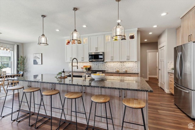 3222 W Harvard Dr, Mountain Green, UT 84050 - kitchen featuring appliances with stainless steel finishes, decorative backsplash, dark wood-style floors, a breakfast bar area, and a center island with sink