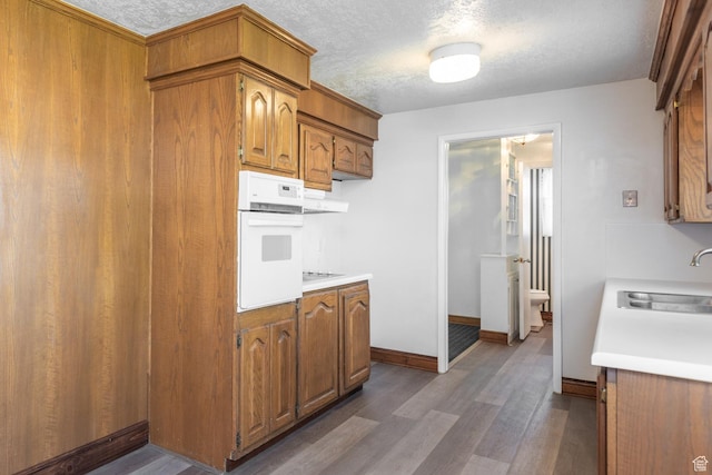 570 N Parkway Ave, Tooele, UT 84074 - kitchen featuring a sink, oven, light countertops, dark wood-style floors, and brown cabinets