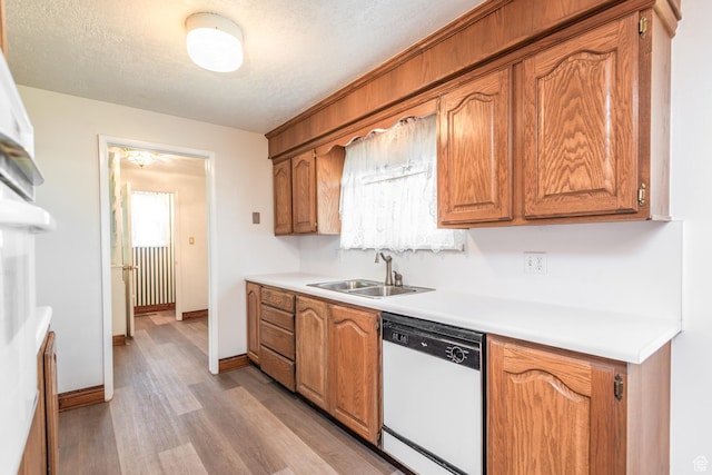 570 N Parkway Ave, Tooele, UT 84074 - kitchen with dishwasher, a sink, light wood-style floors, light countertops, and a textured ceiling
