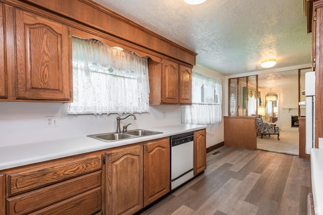 570 N Parkway Ave, Tooele, UT 84074 - kitchen with white dishwasher, a sink, a textured ceiling, brown cabinetry, and wood finished floors