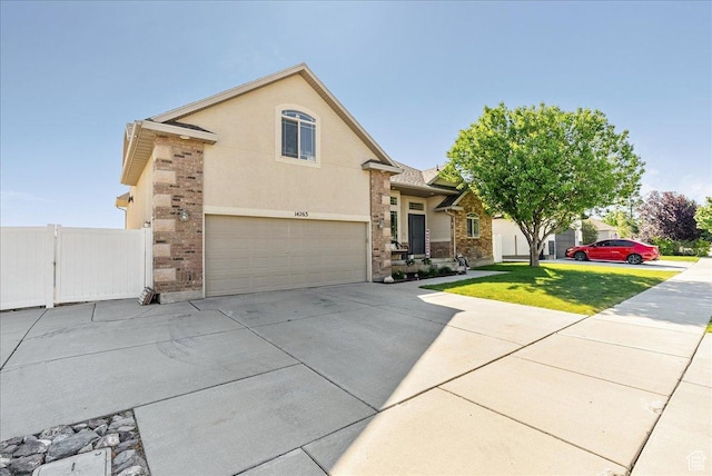 14263 S Morning Light Dr W, Herriman, UT 84065 - view of front of house featuring driveway, an attached garage, stucco siding, and stone siding