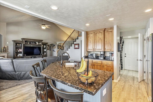 14263 S Morning Light Dr W, Herriman, UT 84065 - kitchen with light wood-type flooring, a sink, a breakfast bar area, ceiling fan, and lofted ceiling