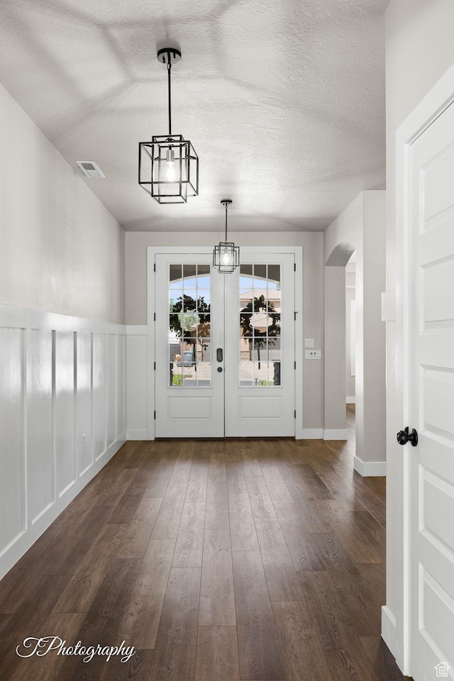 3643 S 2870 E, St George, UT 84790 - unfurnished dining area with arched walkways, dark wood-style floors, a textured ceiling, and a wainscoted wall