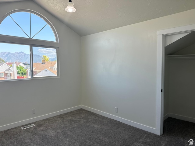 9152 S Cripple Creek Cir W, West Jordan, UT 84088 - unfurnished bedroom with vaulted ceiling, dark carpet, a textured ceiling, baseboards, and a walk in closet