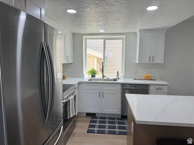 9152 S Cripple Creek Cir W, West Jordan, UT 84088 - kitchen featuring stainless steel appliances, a textured ceiling, a sink, light wood finished floors, and recessed lighting
