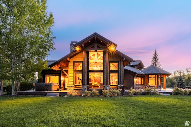 1198 E Elkhorn Ln Unit 2, Oakley, UT 84055 - back of property at dusk featuring a yard, covered porch, a chimney, a hot tub, and stone siding