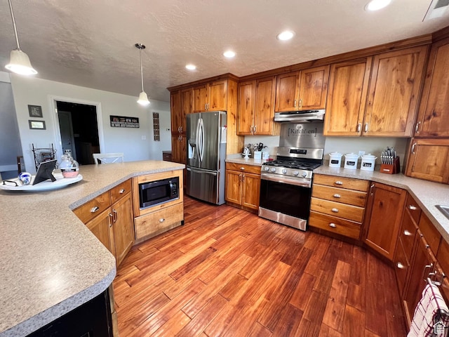 505 W 300 N, Orangeville, UT 84537 - kitchen featuring stainless steel appliances, brown cabinetry, wood finished floors, under cabinet range hood, and light countertops