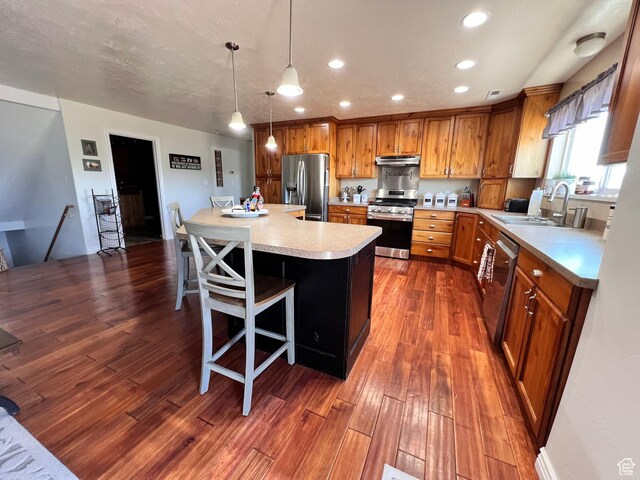 505 W 300 N, Orangeville, UT 84537 - kitchen with appliances with stainless steel finishes, under cabinet range hood, light countertops, brown cabinetry, and a sink