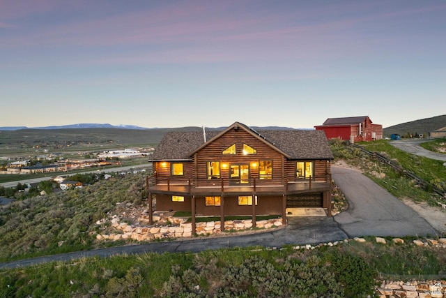 6380 N Silver Sage Dr, Park City, UT 84098 - back of property at dusk with log siding, roof with shingles, a deck with mountain view, and an attached garage