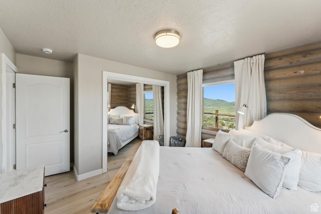 6380 N Silver Sage Dr, Park City, UT 84098 - bedroom featuring light wood-style floors, baseboards, a textured ceiling, log walls, and a mountain view
