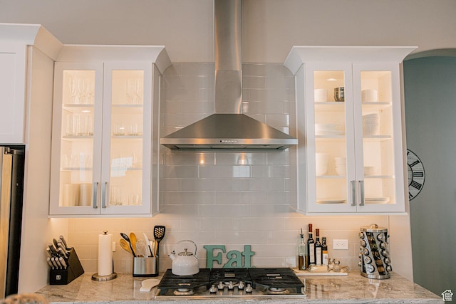 5028 W Lake Terrace Ave, South Jordan, UT 84009 - kitchen with wall chimney range hood, stainless steel gas stovetop, decorative backsplash, arched walkways, and light stone counters