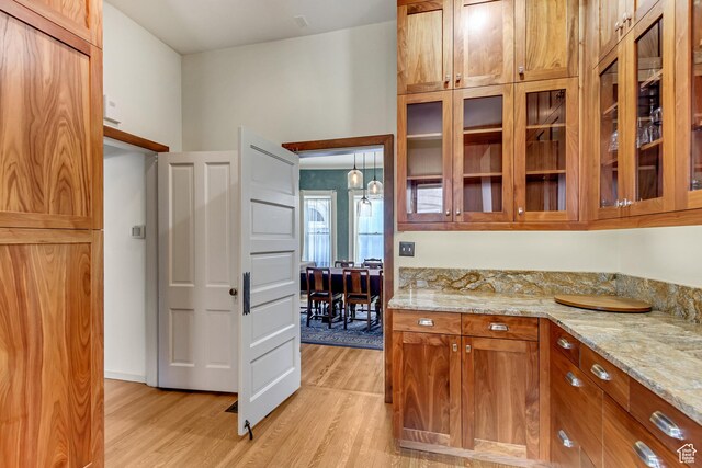 15 S 1200 E, Salt Lake City, UT 84102 - kitchen with light wood-style floors, brown cabinetry, light stone counters, and glass insert cabinets