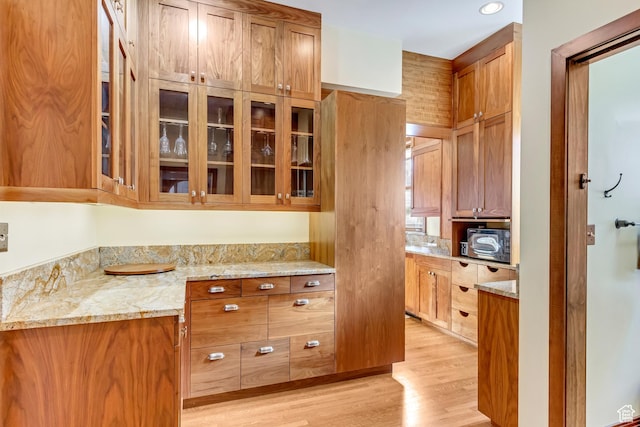 15 S 1200 E, Salt Lake City, UT 84102 - kitchen with light wood-style floors, light stone countertops, glass insert cabinets, and brown cabinetry