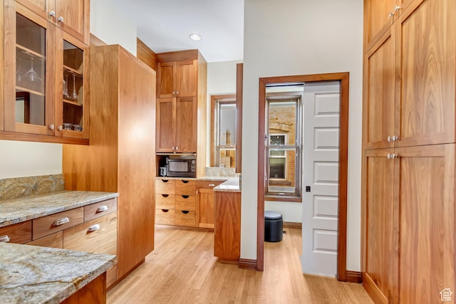 15 S 1200 E, Salt Lake City, UT 84102 - kitchen featuring light wood-type flooring, light stone countertops, glass insert cabinets, brown cabinets, and baseboards