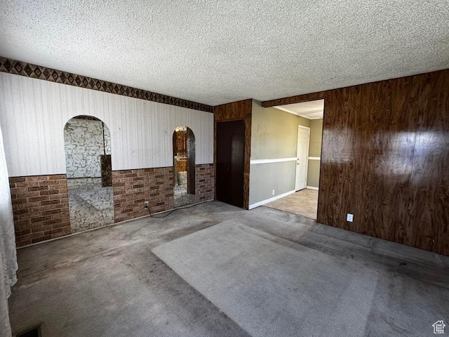 635 N Chimesview Cir E, Tooele, UT 84074 - carpeted spare room featuring arched walkways, wood walls, a textured ceiling, and a wainscoted wall