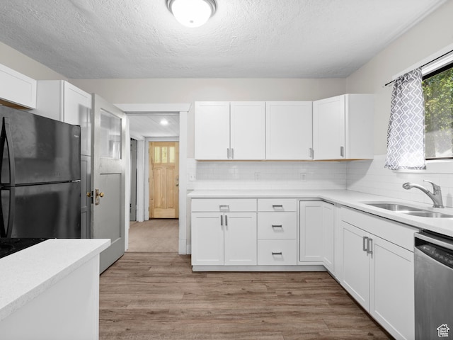 719 E 22nd St, Ogden, UT 84401 - kitchen featuring freestanding refrigerator, stainless steel dishwasher, white cabinetry, light countertops, and a textured ceiling