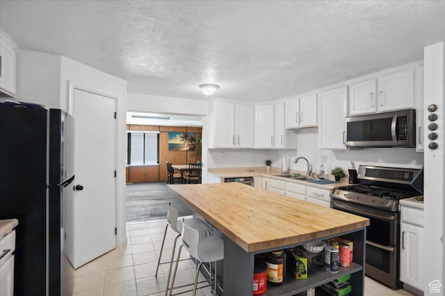 2137 W 6200 S, Salt Lake City, UT 84129 - kitchen with appliances with stainless steel finishes, wooden counters, white cabinets, a sink, and a textured ceiling