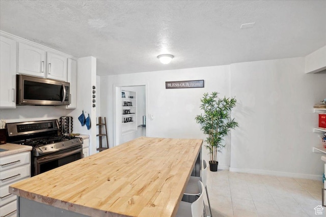 2137 W 6200 S, Salt Lake City, UT 84129 - kitchen with stainless steel appliances, white cabinetry, a kitchen island, wooden counters, and baseboards