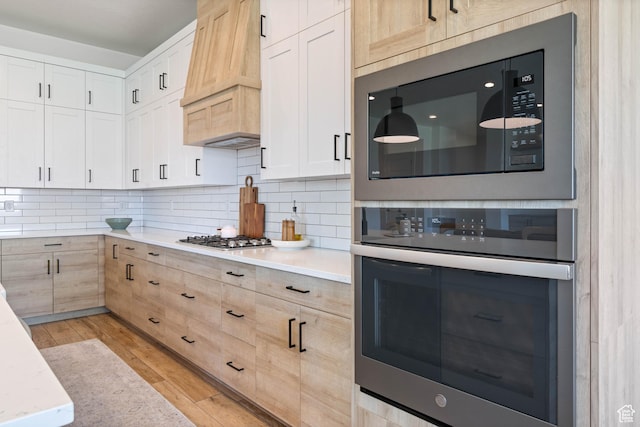3322 S 2240 E, St George, UT 84790 - kitchen with appliances with stainless steel finishes, premium range hood, tasteful backsplash, light wood-style floors, and light brown cabinetry