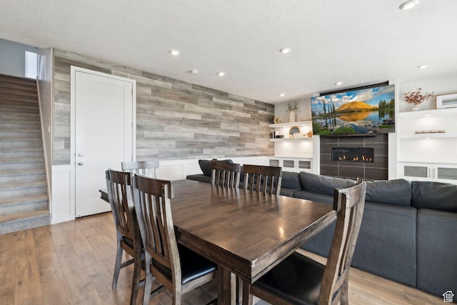 1006 W Firelock Way S, Bluffdale, UT 84065 - dining room featuring stairs, recessed lighting, wood walls, light wood-type flooring, and a tile fireplace