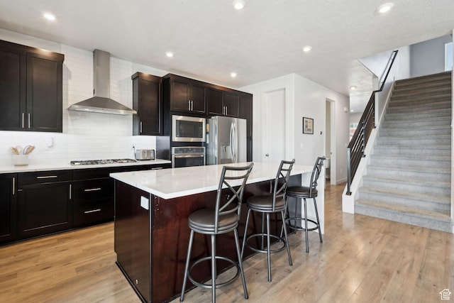 1006 W Firelock Way S, Bluffdale, UT 84065 - kitchen featuring wall chimney range hood, stainless steel appliances, a breakfast bar, a center island, and backsplash