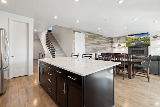 1006 W Firelock Way S, Bluffdale, UT 84065 - kitchen with stainless steel fridge with ice dispenser, light wood finished floors, light stone countertops, a kitchen island, and open floor plan