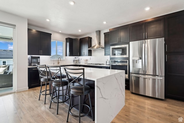 1006 W Firelock Way S, Bluffdale, UT 84065 - kitchen featuring appliances with stainless steel finishes, wall chimney exhaust hood, a breakfast bar, a center island, and light stone counters