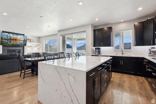 1006 W Firelock Way S, Bluffdale, UT 84065 - kitchen featuring a sink, light wood finished floors, open floor plan, a center island, and a textured ceiling