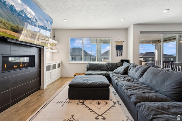 1006 W Firelock Way S, Bluffdale, UT 84065 - living room with light wood finished floors, a fireplace, a textured ceiling, baseboards, and recessed lighting